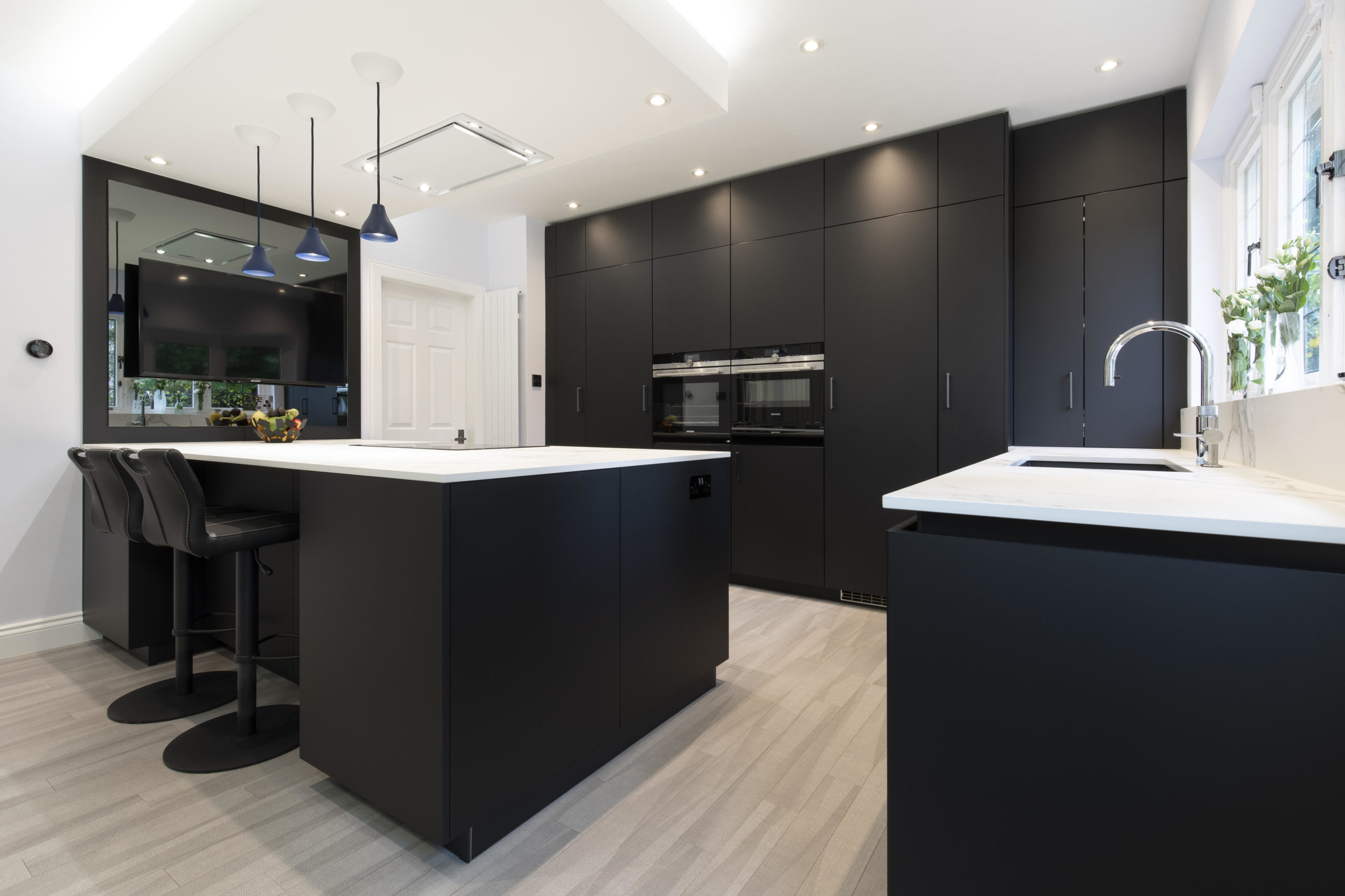 A modern kitchen with white countertops and black cupboards and walls