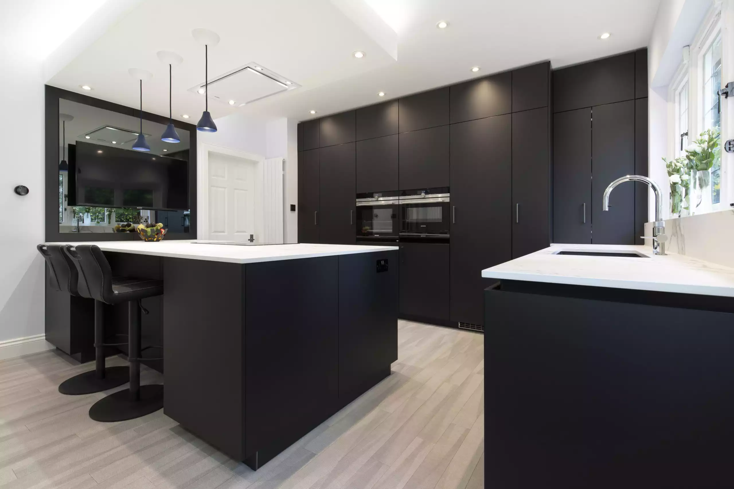 A modern kitchen with white countertops and black cupboards and walls