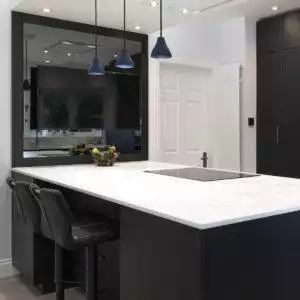 A photo of a Kitchen's International kitchen with white marble surface and black cabinets