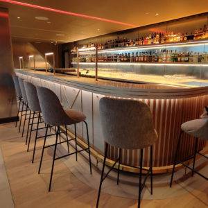 A modern looking bar with warm led lighting reflected in the stone countertop installed by Stonecare