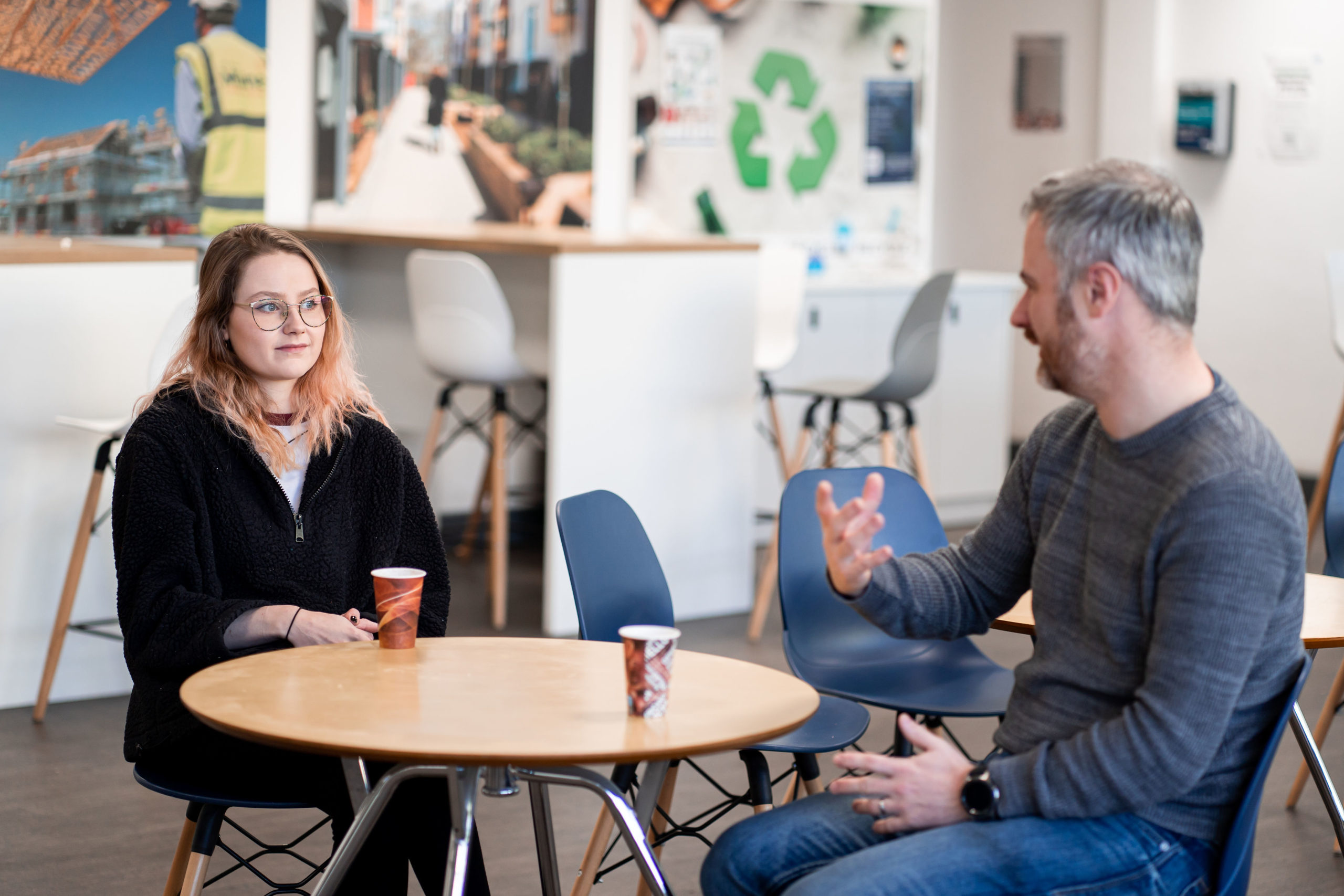 Two members of the JDG sitting at a desk and conversing