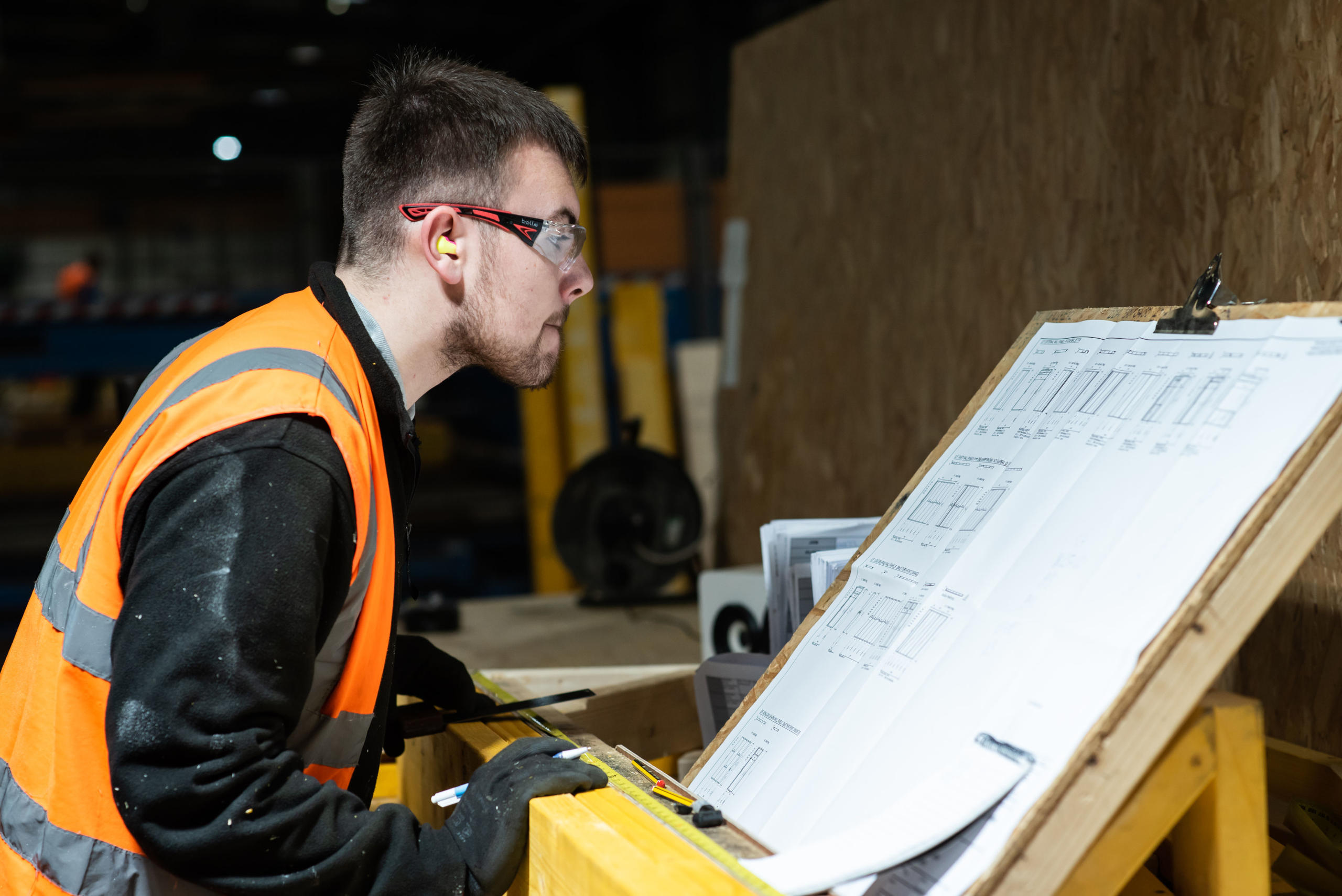 A Donaldson Timber System's employee checking truss plans before marking his wood product for manufacture